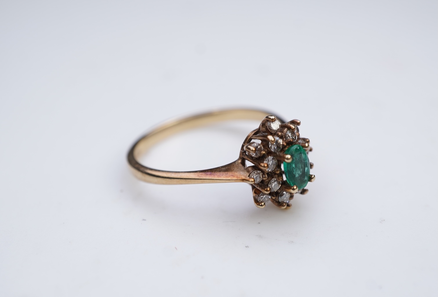 An emerald and diamond cluster ring